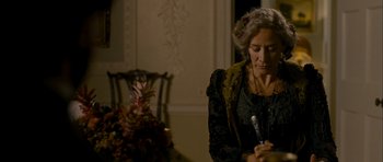 Movie still from “The Woman in Black” (2012), directed by James Watkins – An older woman sitting at a dining room table writing; Medium shot, High angle