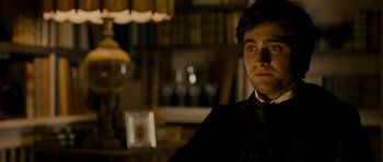 Movie still from “The Woman in Black” (2012), directed by James Watkins – A man in a suit and tie in front of a book case; Close Up shot, Over the shoulder angle
