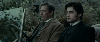 Movie still from “The Woman in Black” (2012), directed by James Watkins – A man sitting next to another man in a field; Close Up shot, Over the shoulder angle