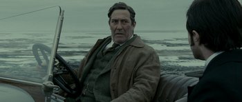 Movie still from “The Woman in Black” (2012), directed by James Watkins – A man sitting on the beach in a brown jacket; Close Up shot, Over the shoulder angle