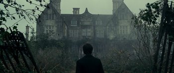 Movie still from “The Woman in Black” (2012), directed by James Watkins – A man standing in front of an old mansion; Wide shot, Low angle