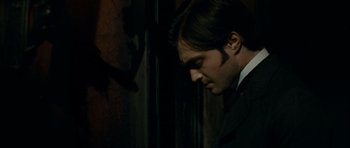 Movie still from “The Woman in Black” (2012), directed by James Watkins – A man in a black suit looking down at his face; Close Up shot, Over the shoulder angle