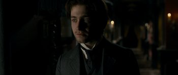 Movie still from “The Woman in Black” (2012), directed by James Watkins – A man in a suit and tie in a dimly - lit room; Close Up shot, Over the shoulder angle