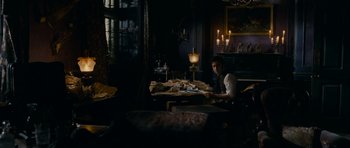 Movie still from “The Woman in Black” (2012), directed by James Watkins – A man sitting at a table in front of candles; Wide shot, High angle