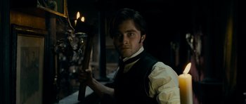 Movie still from “The Woman in Black” (2012), directed by James Watkins – A man in a vest holding a cane in a dark room; Medium shot, Low angle