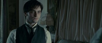 Movie still from “The Woman in Black” (2012), directed by James Watkins – A man in a suit and tie in front of a lamp; Close Up shot, Over the shoulder angle