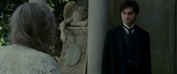 Movie still from “The Woman in Black” (2012), directed by James Watkins – A man standing next to an angel statue; Medium shot, Over the shoulder angle
