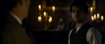 Movie still from “The Woman in Black” (2012), directed by James Watkins – A man standing in front of candles in a dark room; Close Up shot, Over the shoulder angle