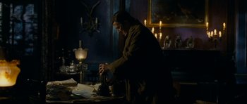 Movie still from “The Woman in Black” (2012), directed by James Watkins – A man is standing in a dark room with papers; Medium shot, Low angle