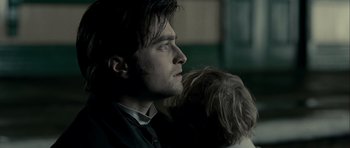 Movie still from “The Woman in Black” (2012), directed by James Watkins – A man holding a dog in his arms and looking into the distance; Close Up shot, Low angle