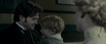 Movie still from “The Woman in Black” (2012), directed by James Watkins – A man and a boy are smiling at each other; Close Up shot, Over the shoulder angle