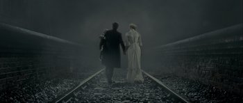 Movie still from “The Woman in Black” (2012), directed by James Watkins – A man and a woman holding hands while walking down a train track; Wide shot, High angle