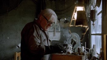 Movie still from “The World's Fastest Indian” (2005), directed by Roger Donaldson – An older man working in a workshop on a piece of metal; Medium shot, Low angle
