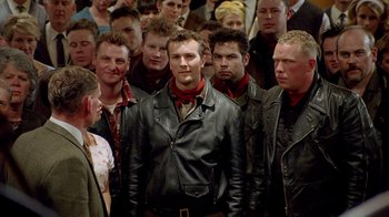 Movie still from “The World's Fastest Indian” (2005), directed by Roger Donaldson – A group of men standing next to each other in a crowd; Medium shot, Over the shoulder angle