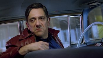 Movie still from “The World's Fastest Indian” (2005), directed by Roger Donaldson – A man sitting in a car looking at the camera; Close Up shot, Low angle