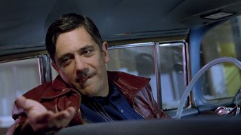 Movie still from “The World's Fastest Indian” (2005), directed by Roger Donaldson – A person sitting in a car wearing a jacket; Close Up shot, Over the shoulder angle