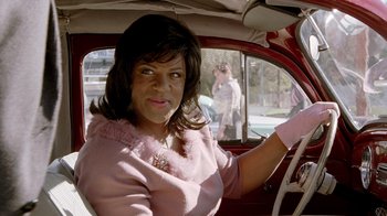 Movie still from “The World's Fastest Indian” (2005), directed by Roger Donaldson – A woman sitting in the driver's seat of a car; Close Up shot, Over the shoulder angle