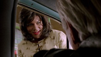 Movie still from “The World's Fastest Indian” (2005), directed by Roger Donaldson – A woman in a yellow dress looking into a car mirror; Close Up shot, Over the shoulder angle