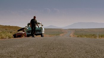 Movie still from “The World's Fastest Indian” (2005), directed by Roger Donaldson – A man standing on the side of a road next to a car; Extreme Wide shot, Low angle