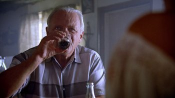 Movie still from “The World's Fastest Indian” (2005), directed by Roger Donaldson – An older man drinking a glass of beer; Close Up shot, Over the shoulder angle