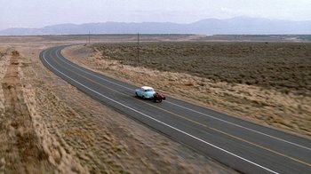 Movie still from “The World's Fastest Indian” (2005), directed by Roger Donaldson – A car driving down the middle of a road; Extreme Wide shot, High angle