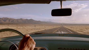 Movie still from “The World's Fastest Indian” (2005), directed by Roger Donaldson – A man driving a car on a road with mountains in the background; Wide shot, Low angle