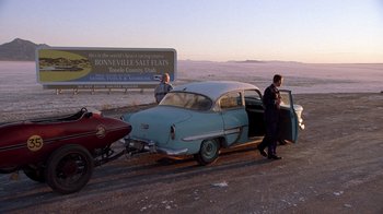 Movie still from “The World's Fastest Indian” (2005), directed by Roger Donaldson – Two men are standing next to an old car; Extreme Wide shot, High angle