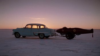 Movie still from “The World's Fastest Indian” (2005), directed by Roger Donaldson – An old car is pulling a boat on a trailer; Extreme Wide shot, Low angle