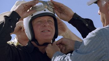 Movie still from “The World's Fastest Indian” (2005), directed by Roger Donaldson – A man putting on a motorcycle helmet while another man adjusts his goggles; Close Up shot, Low angle