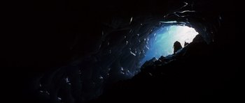 Movie still from “The X Files” (1998), directed by Rob Bowman – A man standing in a cave looking into the light; Extreme Wide shot, High angle