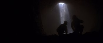 Movie still from “The X Files” (1998), directed by Rob Bowman – Two men are climbing up the side of a cave; Wide shot, Low angle