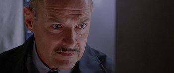 Movie still from “The X Files” (1998), directed by Rob Bowman – An older man with a goatee looking at the camera; Close Up shot, Low angle