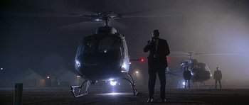 Movie still from “The X Files” (1998), directed by Rob Bowman – A man standing next to a helicopter at night; Wide shot, Low angle