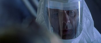 Movie still from “The X Files” (1998), directed by Rob Bowman – A man wearing a face shield looking at the camera; Close Up shot, Over the shoulder angle