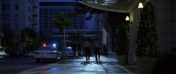 Movie still from “The X Files” (1998), directed by Rob Bowman – Two police officers walking down the sidewalk at night; Extreme Wide shot, Low angle
