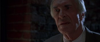 Movie still from “The X Files” (1998), directed by Rob Bowman – An older man in a white shirt and tie; Close Up shot, Over the shoulder angle