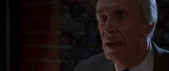 Movie still from “The X Files” (1998), directed by Rob Bowman – An older man in a gray suit looking at the camera; Close Up shot, Over the shoulder angle