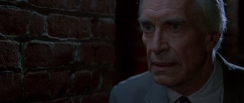 Movie still from “The X Files” (1998), directed by Rob Bowman – An older man in a white suit stares at the camera; Close Up shot, High angle