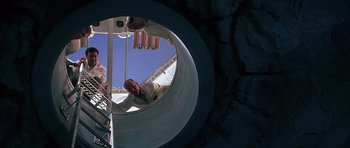 Movie still from “The X Files” (1998), directed by Rob Bowman – A man standing inside of a metal structure; Wide shot, Low angle
