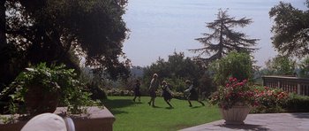 Movie still from “The X Files” (1998), directed by Rob Bowman – A group of people playing frisbee in a yard; Extreme Wide shot, High angle