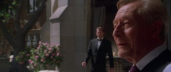 Movie still from “The X Files” (1998), directed by Rob Bowman – A man in a suit standing next to another man in a suit; Close Up shot, Over the shoulder angle