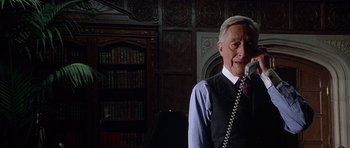 Movie still from “The X Files” (1998), directed by Rob Bowman – An older man talking on a phone in a room; Close Up shot, Low angle