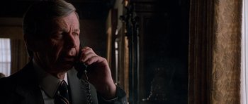 Movie still from “The X Files” (1998), directed by Rob Bowman – An older man talking on a phone in a dark room; Close Up shot, Low angle