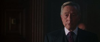 Movie still from “The X Files” (1998), directed by Rob Bowman – An older man wearing a suit and purple tie; Close Up shot, Over the shoulder angle