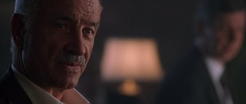 Movie still from “The X Files” (1998), directed by Rob Bowman – An older man with a mustache and a mustache stand in front of a lamp; Close Up shot, Low angle