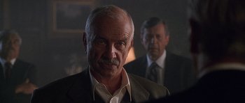 Movie still from “The X Files” (1998), directed by Rob Bowman – A man in a suit and tie standing next to another man in a suit and tie; Close Up shot, Over the shoulder angle