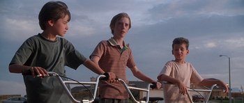 Movie still from “The X Files” (1998), directed by Rob Bowman – Three young boys are riding their bikes together; Medium shot, Low angle