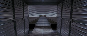 Movie still from “The X Files” (1998), directed by Rob Bowman – An escalator in an enclosed area with no people in it; Extreme Wide shot, Overhead angle