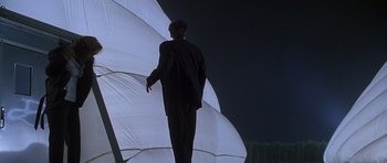 Movie still from “The X Files” (1998), directed by Rob Bowman – A man standing next to an umbrella in the dark; Wide shot, Low angle
