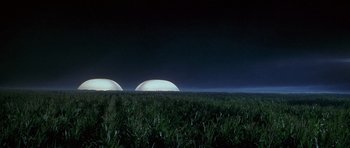 Movie still from “The X Files” (1998), directed by Rob Bowman – A field with grass in the foreground and two domes in the background; Extreme Wide shot, Low angle